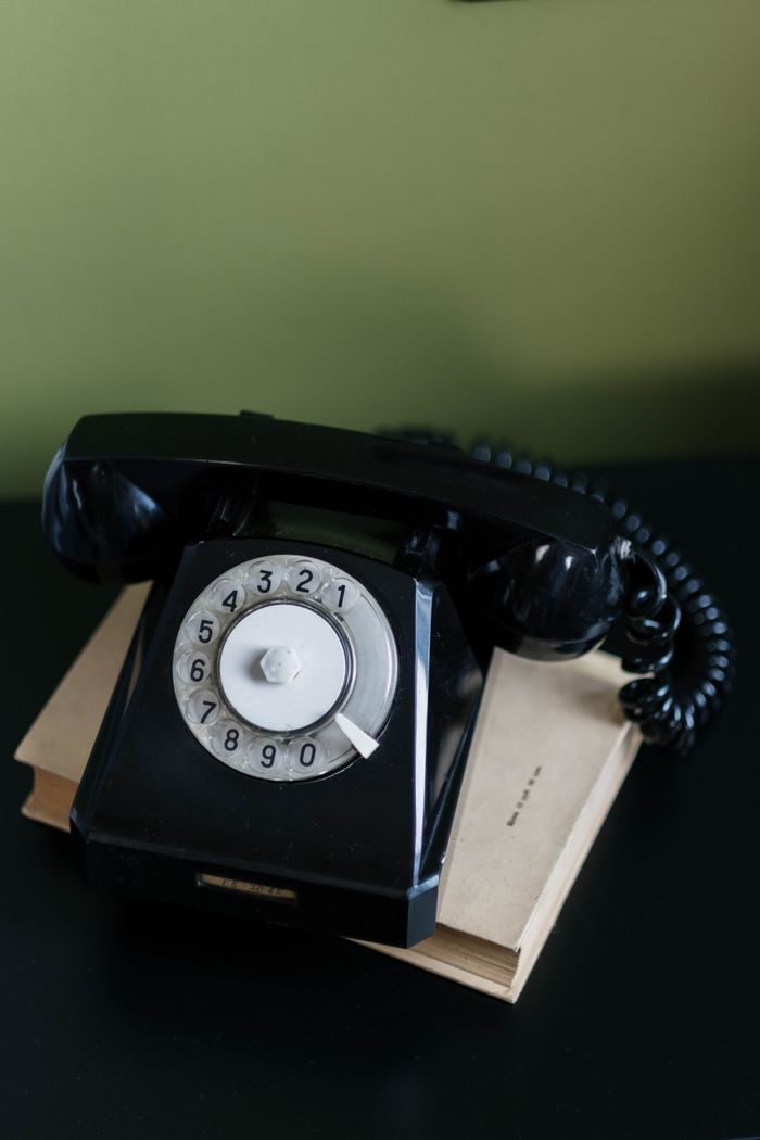 Close-up of a classic black rotary telephone on a desk, evoking nostalgia and retro vibes.